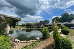 4.-zicht-over-grot-vijver-en-huis-met-donkere-wolken